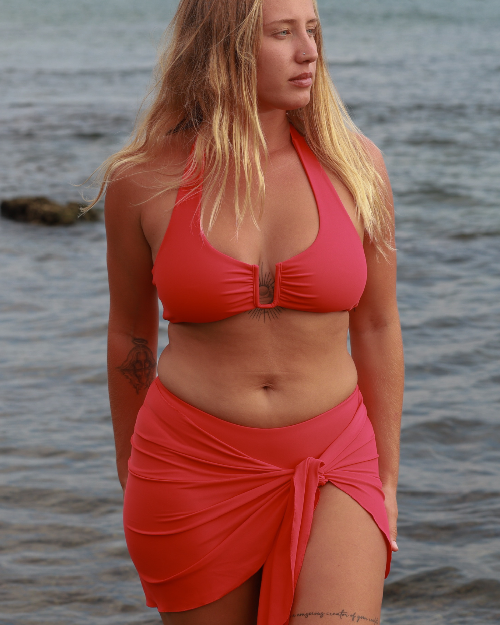 A woman wearing a stylish red bikini at the beach with an ocean view
