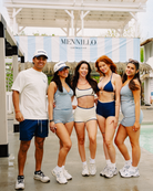 Five people posing in matching swimwear sets from Mennillo Swimwear at the beachclub under a white patio 