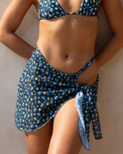 Woman wearing a blooming blue print swimsuit with a sarong with her hands behind her waist