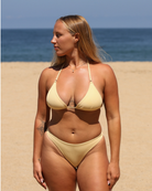 Woman standing on the beach wearing a yellow bikini set and looking away