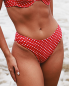 Close-up of a red polka dot bikini bottom on a tan woman