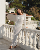 Woman in a white dress standing on a balcony with a scenic background