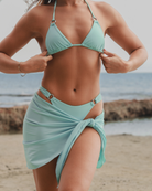 Women wearing a turquoise matte bikini and sarong on a beach