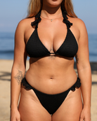 Woman a on a beach wearing a knitted bikini set with ruffles