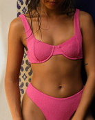 Person wearing a pink bikini against a neutral background